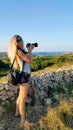 Blonde girl with a camera with a large lens shooting outdoor