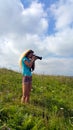 Blonde girl with a camera with a large lens shooting outdoor