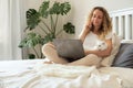 The girl is sitting on the bed with a laptop and makes online purchases Royalty Free Stock Photo