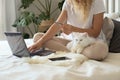 The girl is sitting on the bed with a laptop and makes online purchases Royalty Free Stock Photo