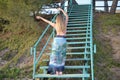 Blonde girl dances on stairs back to the camera with raised arms