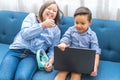 A blonde girl and a dark boy playing happily with a laptop on a sofa Royalty Free Stock Photo