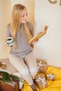 Blonde girl drinking her coffee, eat cookies and read a book Royalty Free Stock Photo