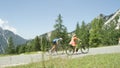 Blonde girl effortlessly pedals past struggling pro road cyclist on sunny road Royalty Free Stock Photo