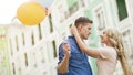 Blonde girl embracing beloved young man, couple dating, holding balloons Royalty Free Stock Photo