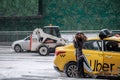 A blonde girl with glasses comes out of a yellow taxi car with the UBER logo