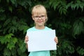 Blonde girl with glasses holding a blank sheet of paper with space for text Royalty Free Stock Photo