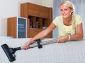 Blonde girl hoovering in living room