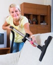 Blonde girl hoovering in living room