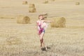 Blonde girl jumps in sloping field Royalty Free Stock Photo