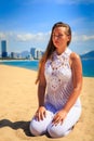 blonde girl in lace sits in yoga asana thunderbolt on beach