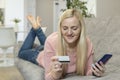 Blonde girl lie on the couch with phone and credit card. concept online shopping Royalty Free Stock Photo