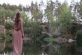 Blonde girl with long beautiful hair in a pink dress on a forest background Royalty Free Stock Photo