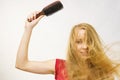 Blonde girl long blowing hair holds natural bristles brush Royalty Free Stock Photo