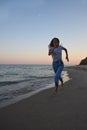 A blonde girl in jeans and a T-shirt is running along the shore of the evening sea Royalty Free Stock Photo