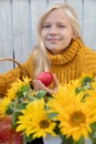 Blonde girl with long hair with sunflowers, holding an apple, photo outdoors, close-up Royalty Free Stock Photo