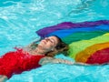 Blonde girl lying relaxed in the water of a swimming pool with an lgtb flag Royalty Free Stock Photo
