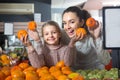 Blonde girl with mother buying mandarins in shop