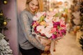 Blonde girl smiles and holds a bouquet of pink orchids and pink roses