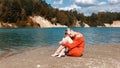 Blonde girl sits on the beach near the blue sea Royalty Free Stock Photo