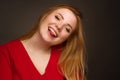 A blonde girl with an overweight plus size, in a red overallposing on a dark Studio background