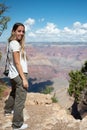 blonde girl with a photo camera in front of the landscape of the Grand Canyon