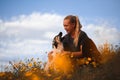 Blonde girl playing with puppy spanish mastiff in a field of yellow flowers Royalty Free Stock Photo