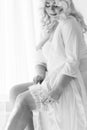 Blonde girl plus size sitting on the bed in white lingerie portrait of Bali morning bride Royalty Free Stock Photo