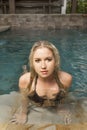 Blonde girl posing in a pool with black swimsuit Royalty Free Stock Photo