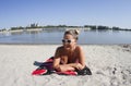 Blonde girl posing on the sand in a bikini swimsuit. Smiling, beautiful, wearing white sunglasses. Royalty Free Stock Photo