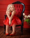 little girl with blond in a red dress in a red room