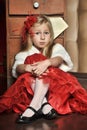 Blonde girl in a red elegant dress with a red hairpin in her hair and a white fur cape Royalty Free Stock Photo