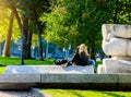 Blonde girl relaxing in the park sitting on the white stone in Milan. Royalty Free Stock Photo