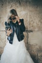 Blonde girl with rock outfit and wedding dress looking her smartphone