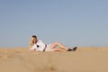 Blonde girl in a shorts and  white shirt lying on send in the biggest European dessert. Hot summer. Oleshki sand, Kherson region i Royalty Free Stock Photo