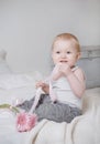 Blonde girl sitting on a bed with pink flowers and ribbon, portrait of a cute baby Royalty Free Stock Photo