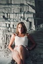 Blonde girl sitting at sandy beach. Outdoor portrait of pretty curly woman. beauty retouch Royalty Free Stock Photo