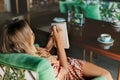 A blonde girl is sitting at a table in a cafe, drinking coffee and making notes in her notebook during a break Royalty Free Stock Photo