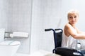 Girl sitting in a wheelchair in a bathroom with the toilet behind Royalty Free Stock Photo