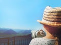 blonde girl with straw hat stands at public telescope in front of swiss mountain scene and clear blue sky Royalty Free Stock Photo