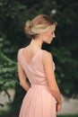 Blonde girl with stylish hairstyle in pink dress. portrait of young woman in spring park. side view Royalty Free Stock Photo