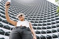 Blonde girl with sunglasses standing in front of a modern building making a selfie with the mobile