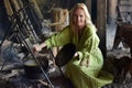 Girl in vintage viking clothing prepares food in a cauldron on a