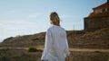 Blonde girl walking castle back view. Calm woman stepping summer landscape alone