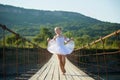 A blonde girl in a white ballet tutu on a bridge in the village Royalty Free Stock Photo