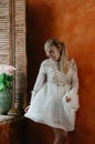 A blonde girl in white dress dancing by the window, flowers Royalty Free Stock Photo