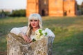 Blonde girl in a white dress on nature near architectural monuments in the open air