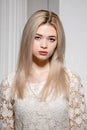 a blonde girl in a white dress poses in a white photo Studio