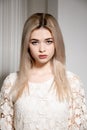 a blonde girl in a white dress poses in a white photo Studio