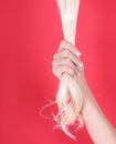 Blonde hair in female hand over red